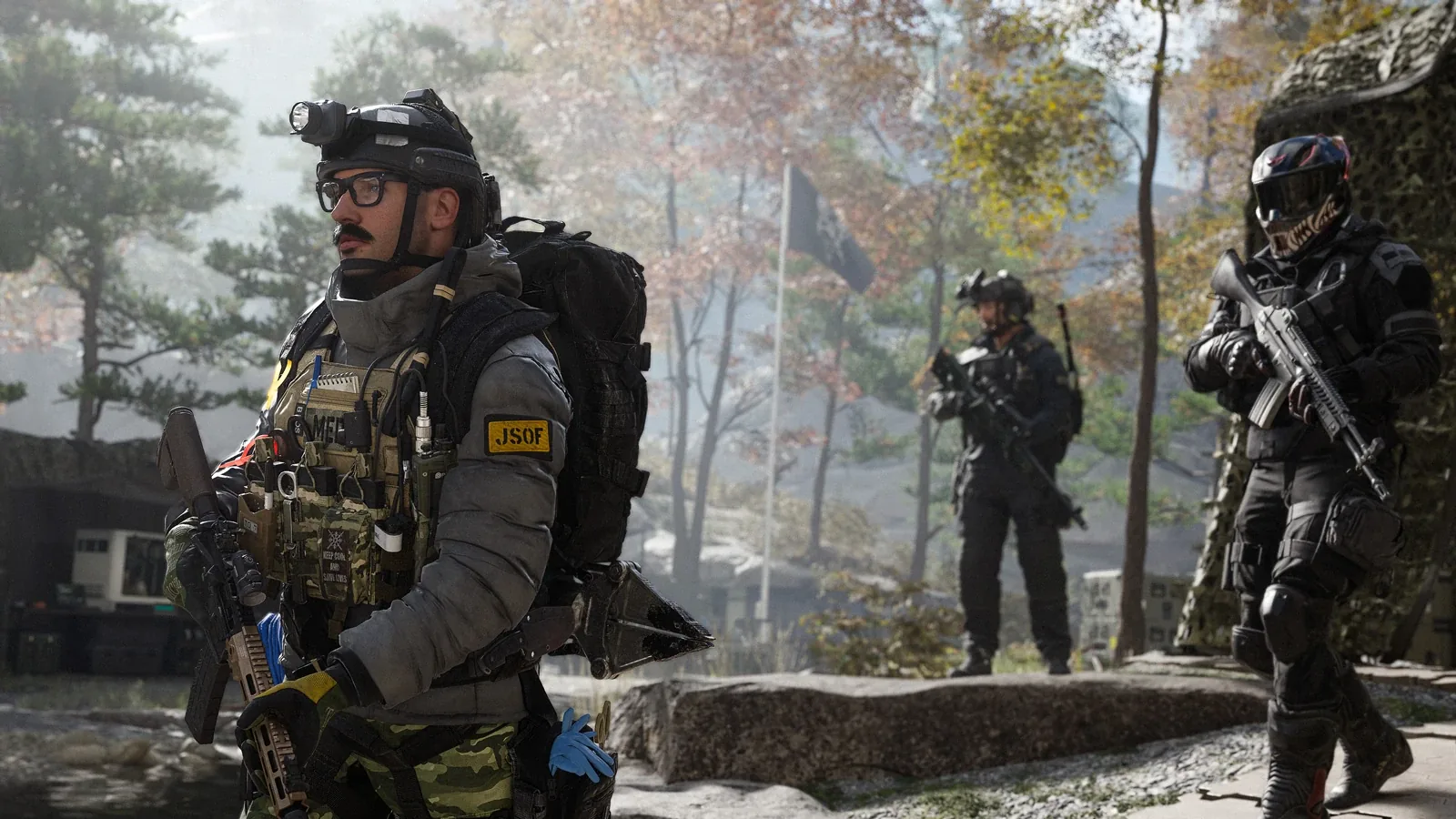 Three armed operators in tactical gear in a misty forest camp, the nearest wearing glasses, a headlamp and a JSOF patch