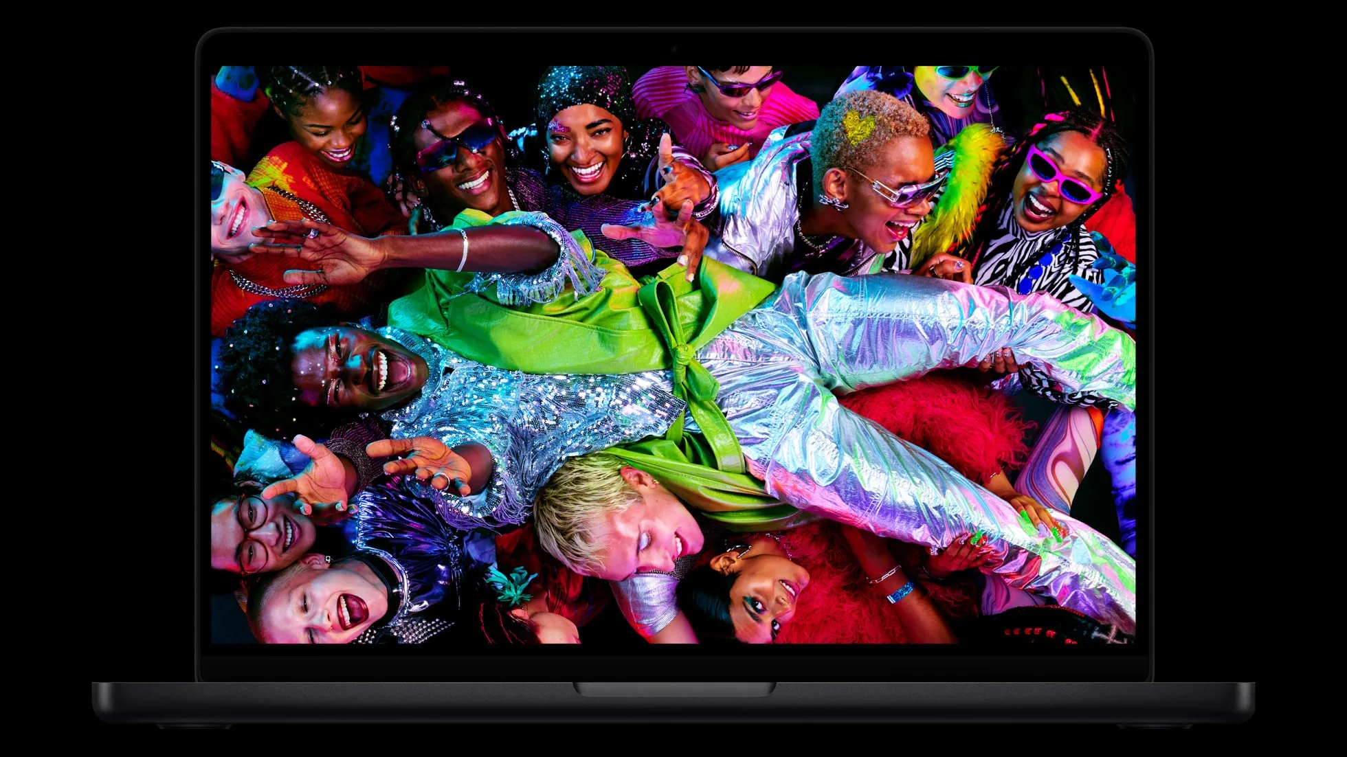 A space black MacBook Pro, open, its screen showing a colorful photo of a crowd in sequins and metallic clothes, on a black background