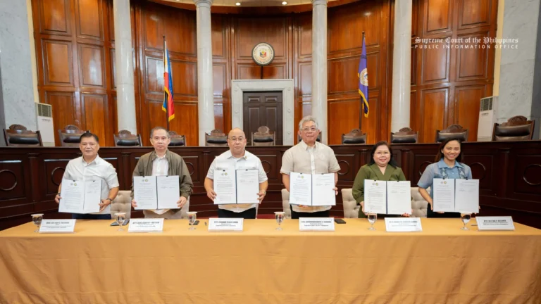 Six Supreme Court and Land Registration Authority officials stand behind a long table in the Supreme Court's session hall, each holding up a signed document