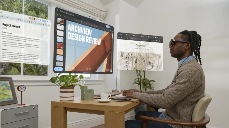 A man at a home-office desk wearing XREAL Aura glasses, with virtual windows for a document, a slide deck and a web browser floating around him