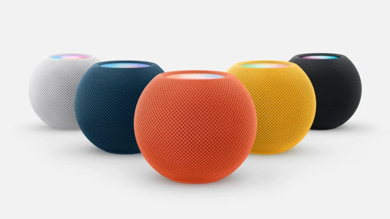 Five HomePod mini smart speakers in white, blue, orange, yellow and dark gray on a light gray background