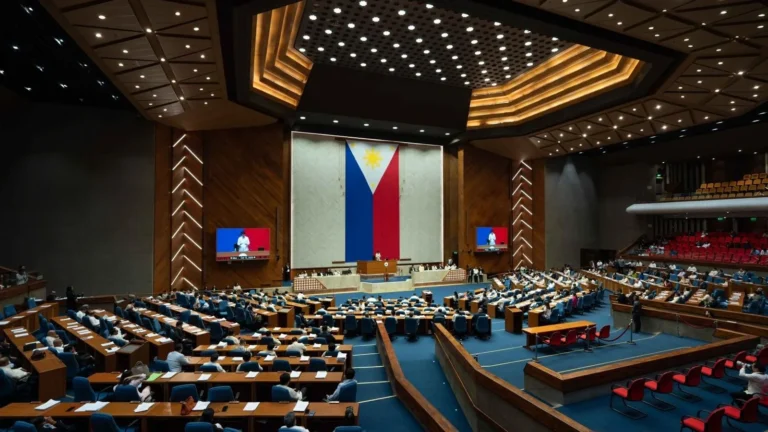 Wide view of the Philippine House of Representatives plenary hall, with lawmakers at their desks below a large Philippine flag