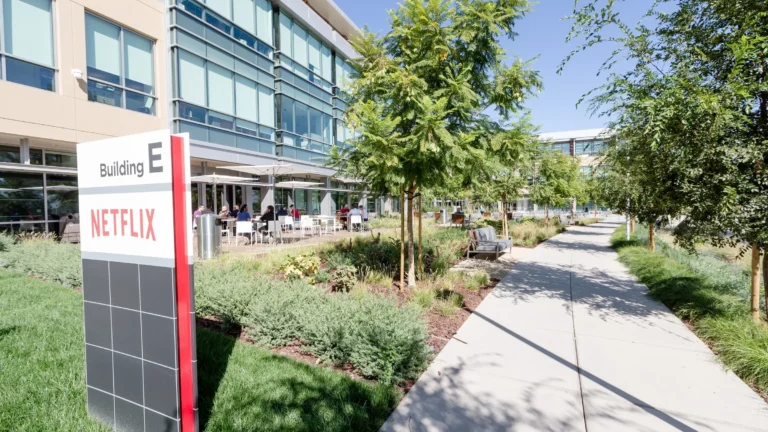 A Netflix Building E sign beside a walkway and outdoor seating at Netflix's office campus