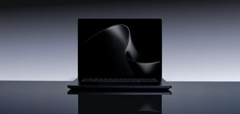 A black Surface Laptop Ultra, open and facing the camera, on a glossy dark surface against a gray gradient background